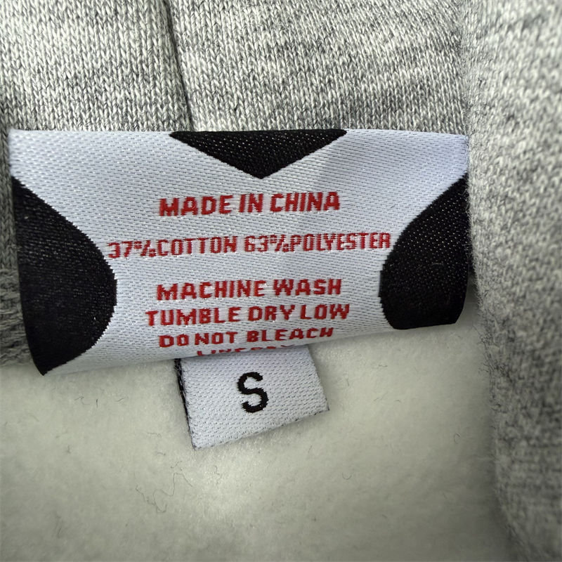 Close-up of a sewn fabric-composition and care label photographed inside a grey Mertra Piping garment